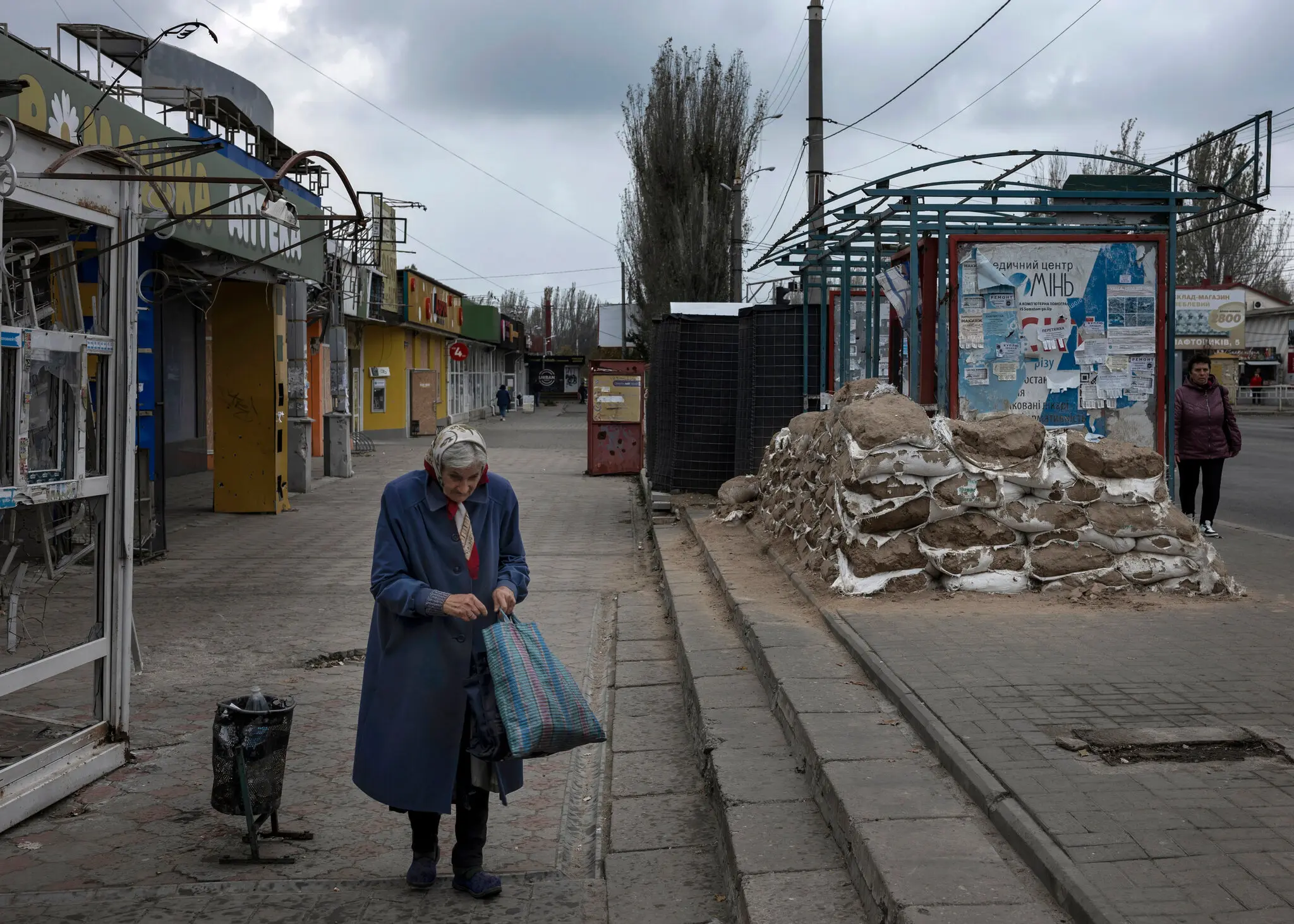 Жінка проходить повз захисні мішки з піском на зупинці в центрі Херсона 1 листопада.